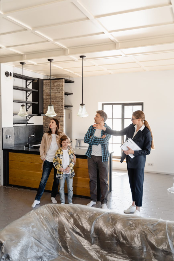 A family tours their new home with a real estate agent in a modern kitchen setting.